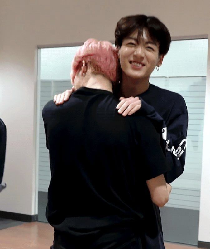 two people are hugging each other in front of a mirror and one person is wearing a black t - shirt