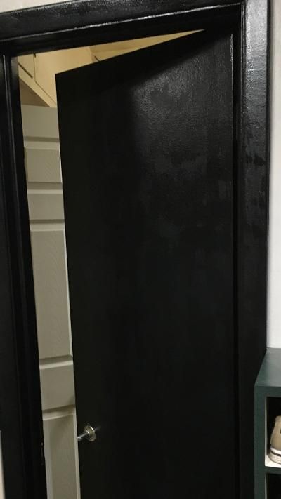 a black door is open in the corner of a room with a shelf and shoes on it