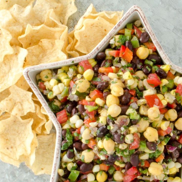 a bowl filled with black beans, corn and salsa next to tortilla chips