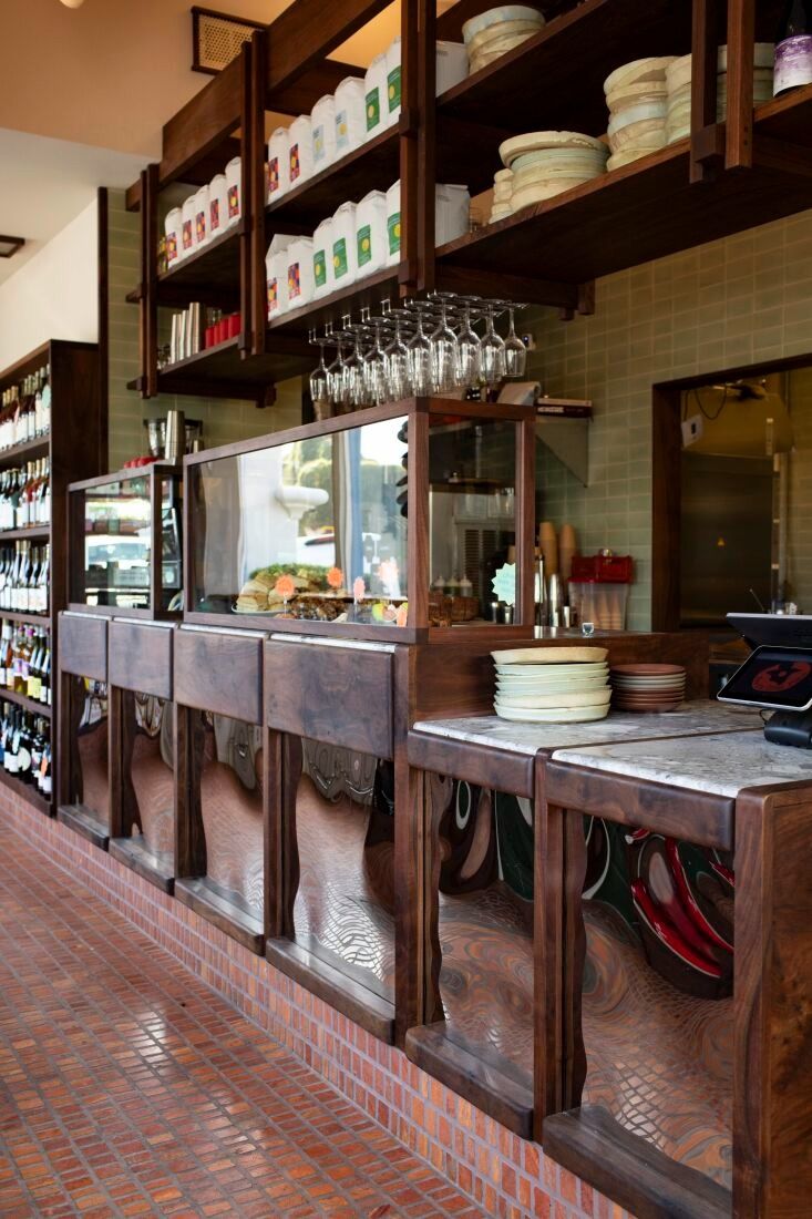 the inside of a restaurant with lots of dishes and glasses on the counter, along with shelves full of wine bottles