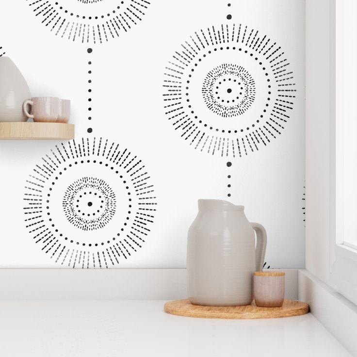 a white vase sitting on top of a counter next to a wall with black dots