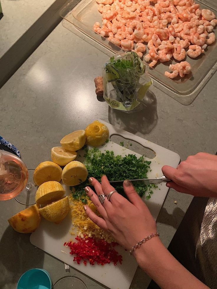 a person cutting up food on top of a white cutting board next to other foods