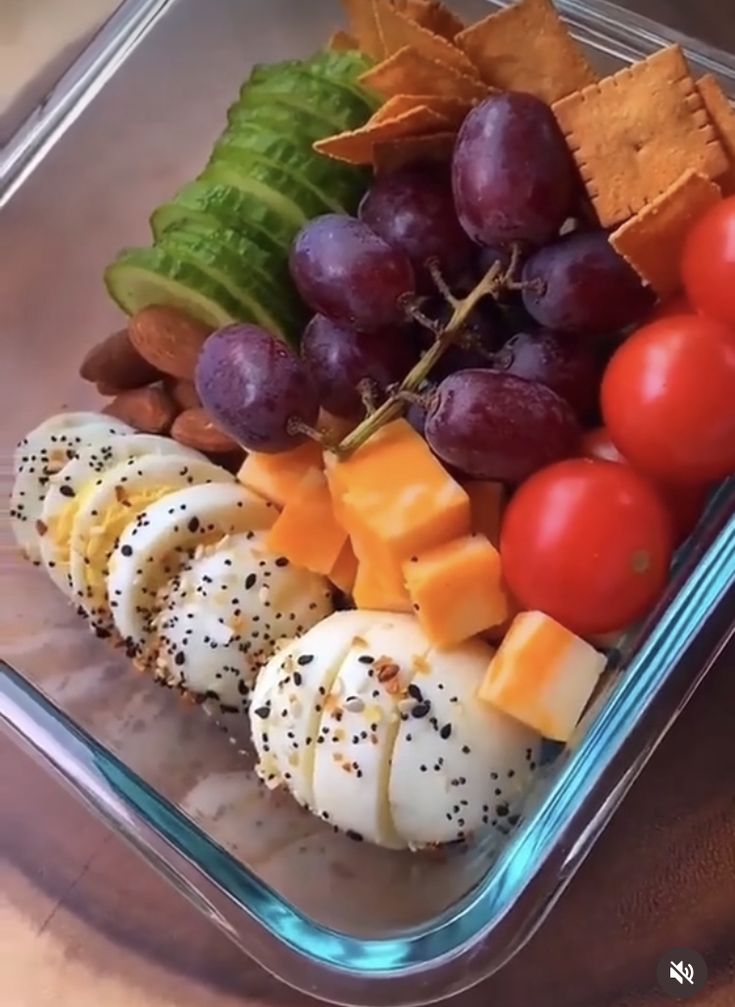 a plastic container filled with different types of fruit and veggies on top of a wooden table