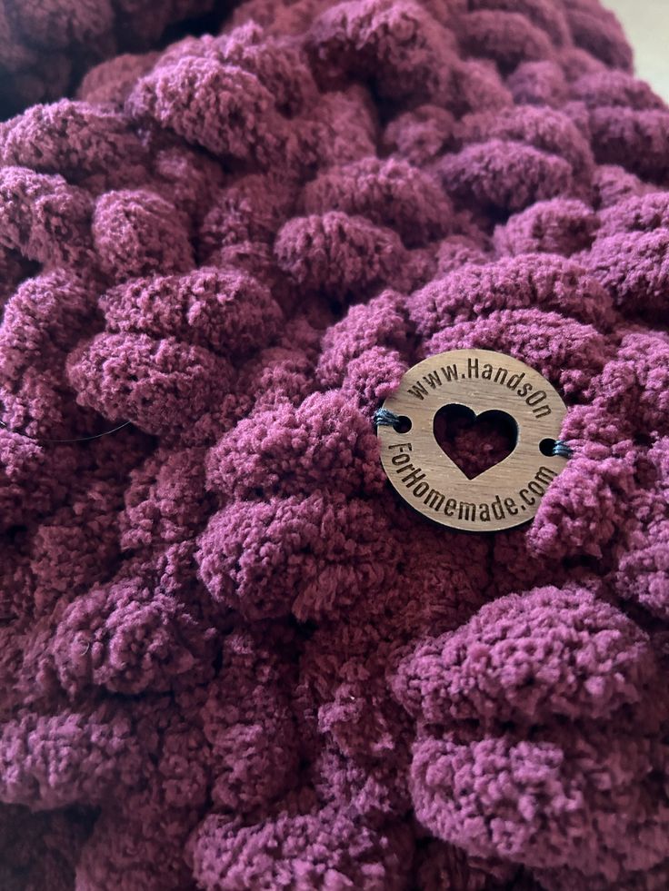 there is a button on the purple crocheted material that looks like it's made from yarn