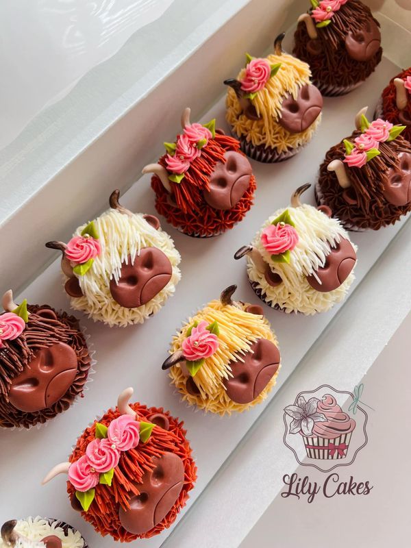 cupcakes with frosting and flowers on them sitting in a white box next to each other