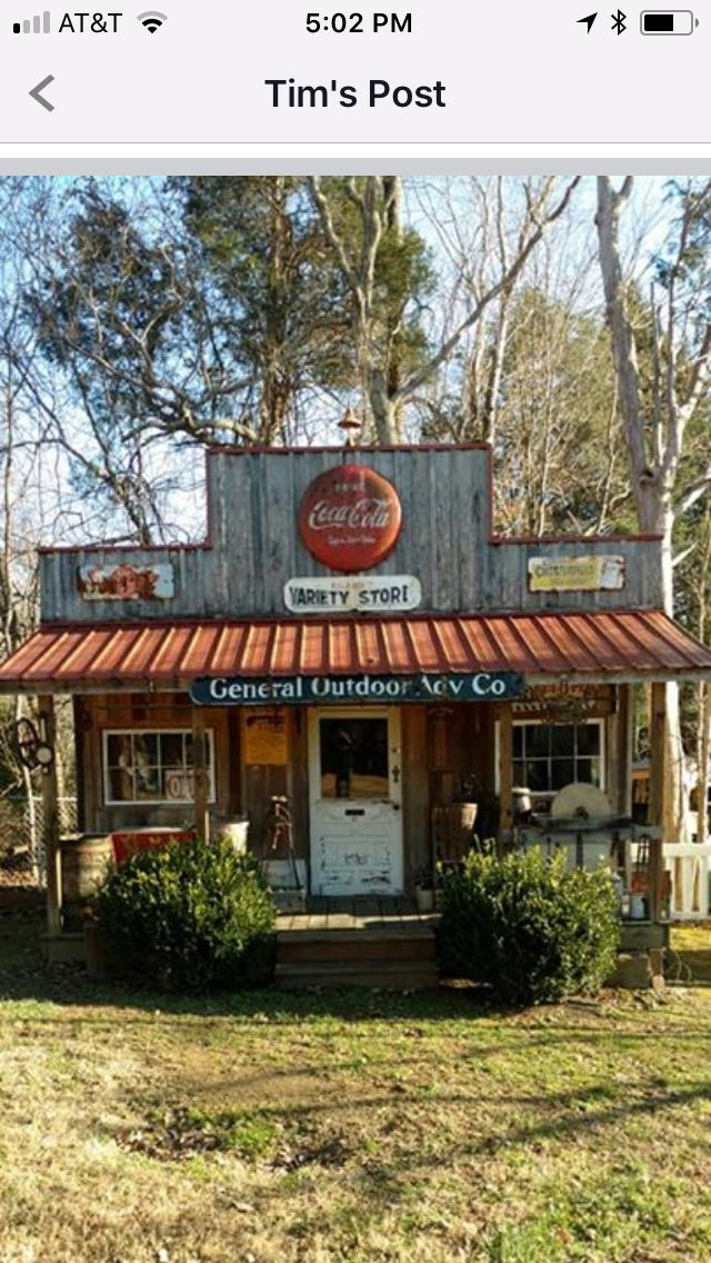 an old fashioned store sitting on the side of a road in front of some trees