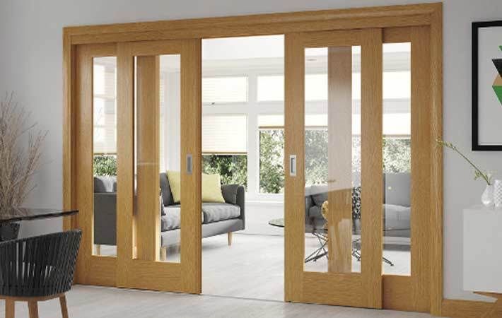 an open living room with sliding glass doors and wood furniture in the background on a white tiled floor