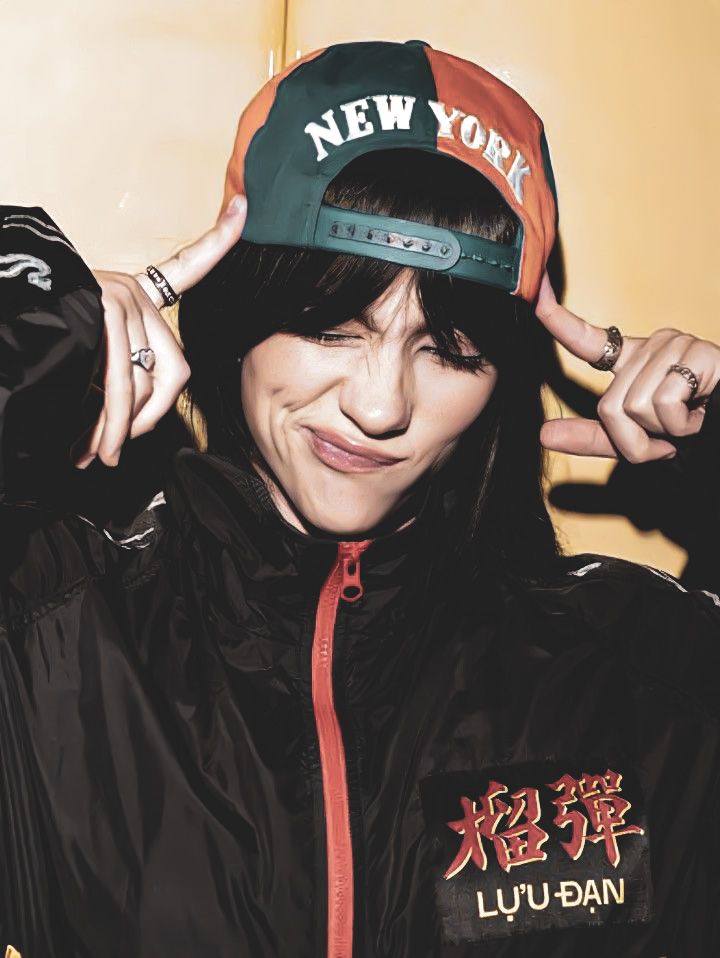 a woman wearing a new york hat while holding her hair in front of her face