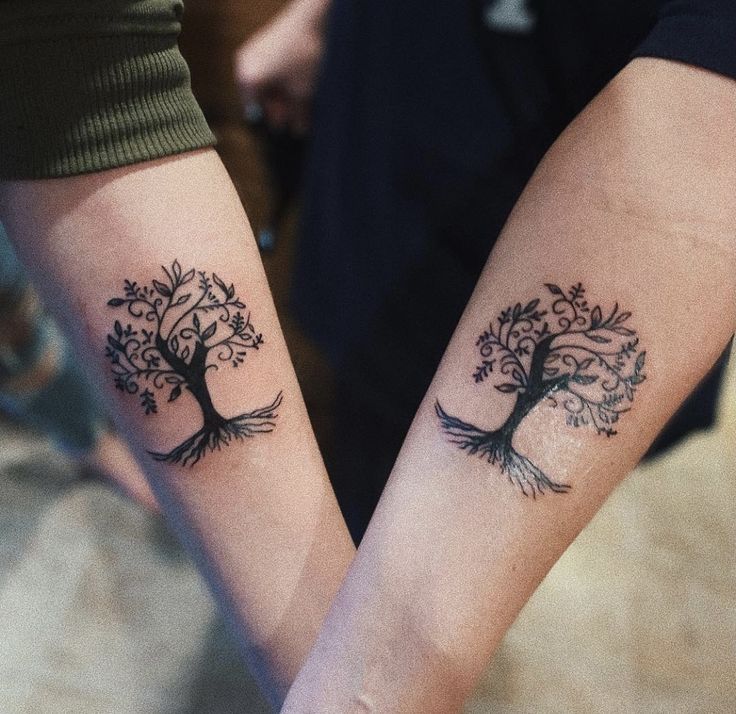 two people holding hands with tattoos on their arms and the other one has a tree