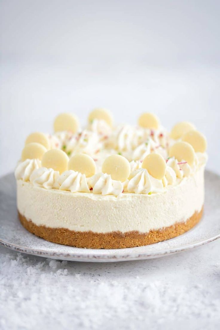 a cheesecake with white icing and toppings on a plate