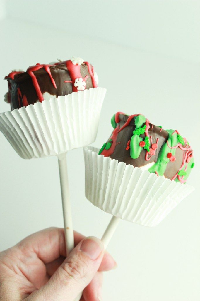 two chocolate covered candy lollipops with sprinkles and green frosting