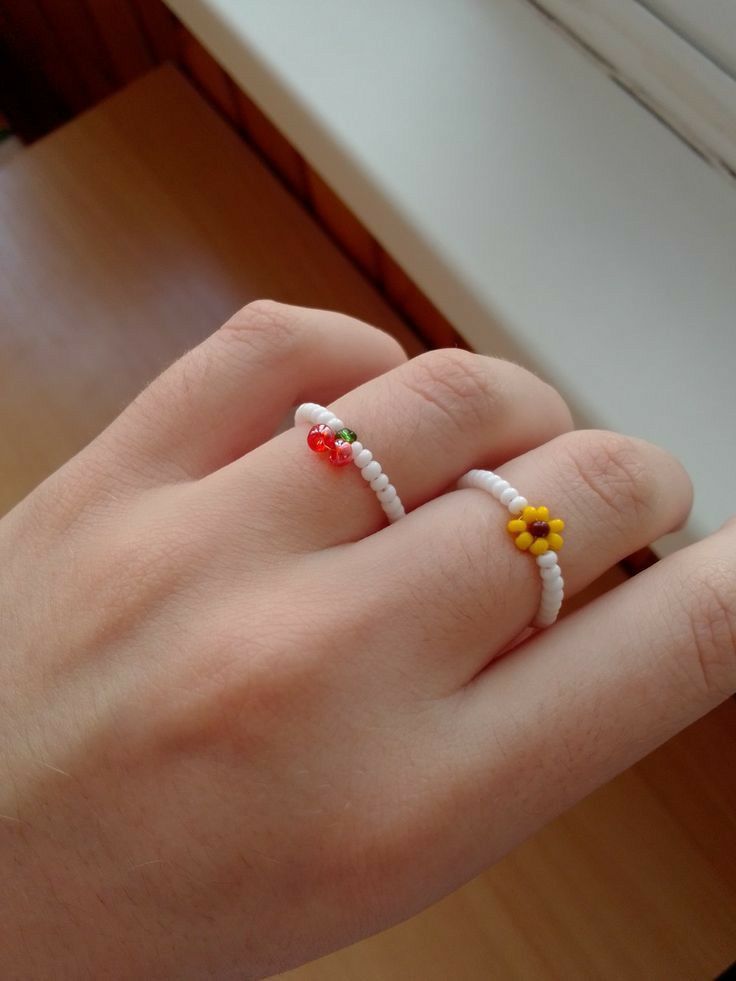 a person's hand with two rings on their fingers and one has flowers in the middle