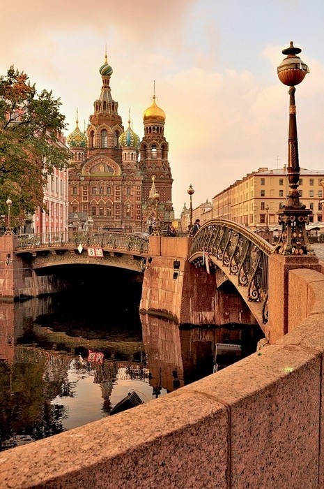 a bridge over a body of water with buildings in the background and a lamp post