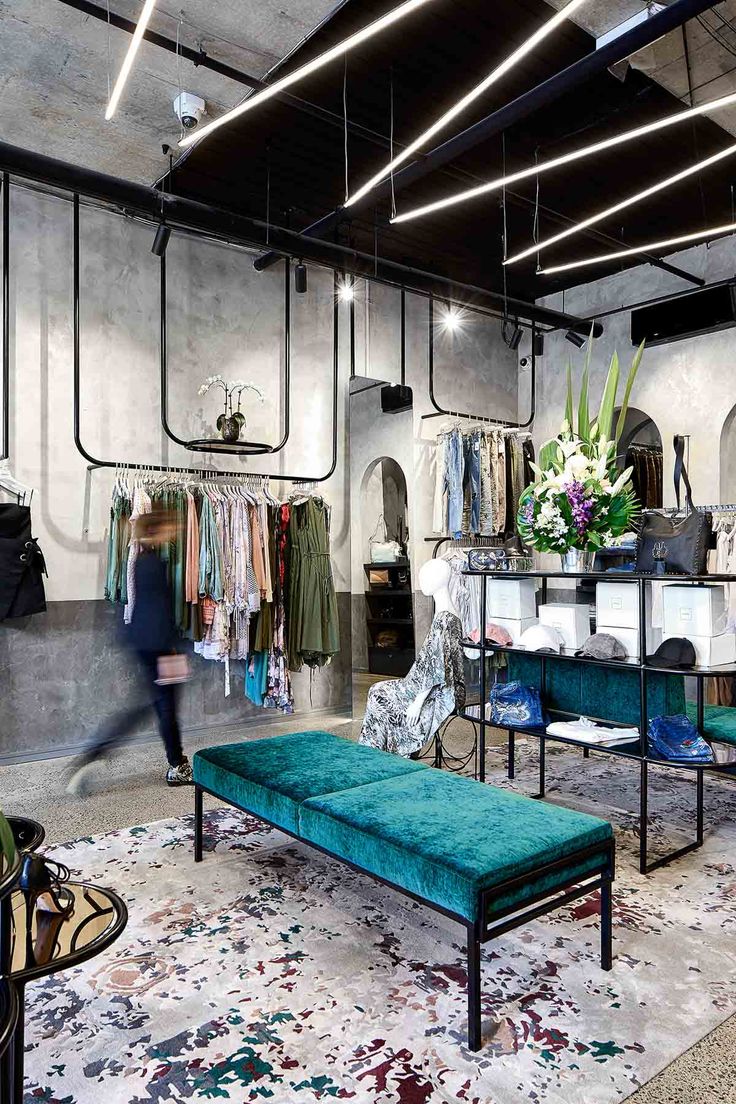 the inside of a clothing store with lots of clothes on display and a bench in front of it