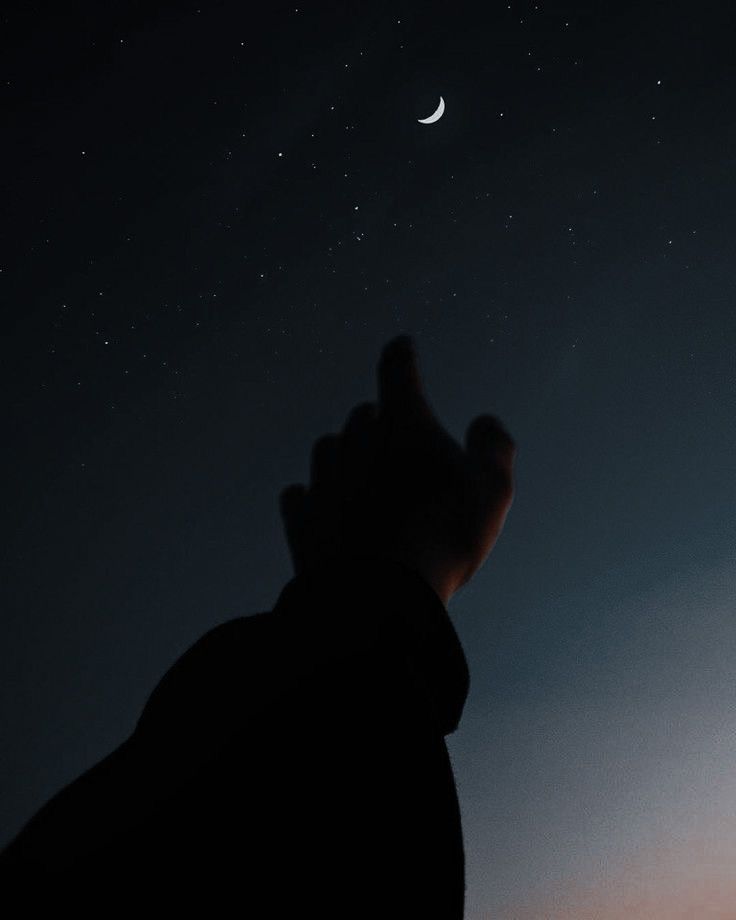 a person is looking up at the moon and stars in the sky with their hands