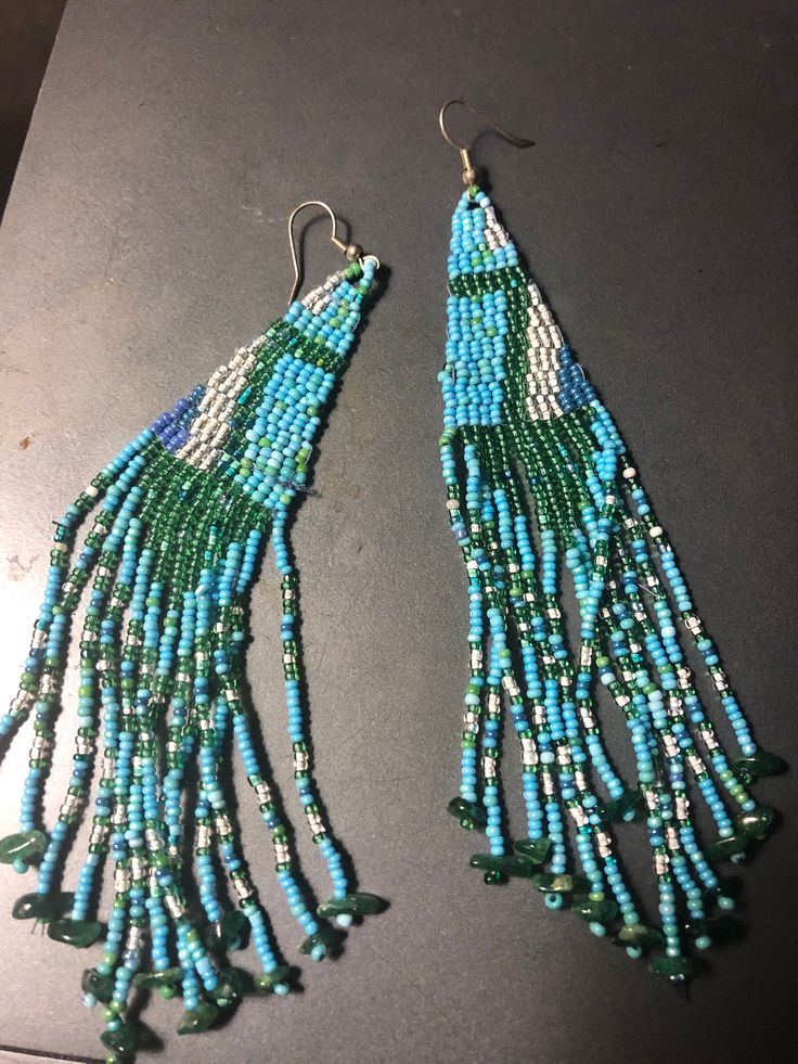 "6.5\" fringed hand beaded earrings with shades of teal, turquoise , white and blues. silver plated ear wires. blessings!" Turquoise Beaded Fringe Tassel Earrings For Festival, Blue Fringe Beaded Earrings, Turquoise Fringe Beaded Earrings For Festival, Turquoise Fringe Earrings With Round Beads, Turquoise Earrings With Fringe And Round Beads, Turquoise Beaded Fringe Dangle Tassel Earrings, Turquoise Fringe Beaded Drop Earrings, Turquoise Beaded Fringe Drop Earrings, Turquoise Fringe Beaded Earrings For Beach