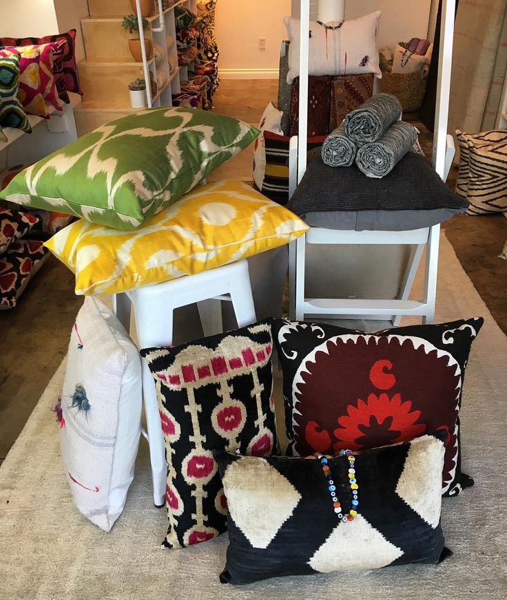 pillows and blankets are stacked on top of each other in a room filled with furniture