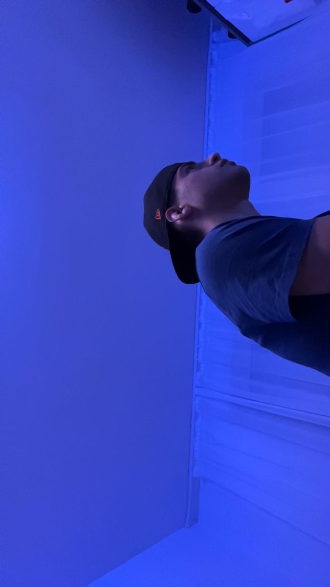 a man is standing in front of a blue light and looking up at the ceiling