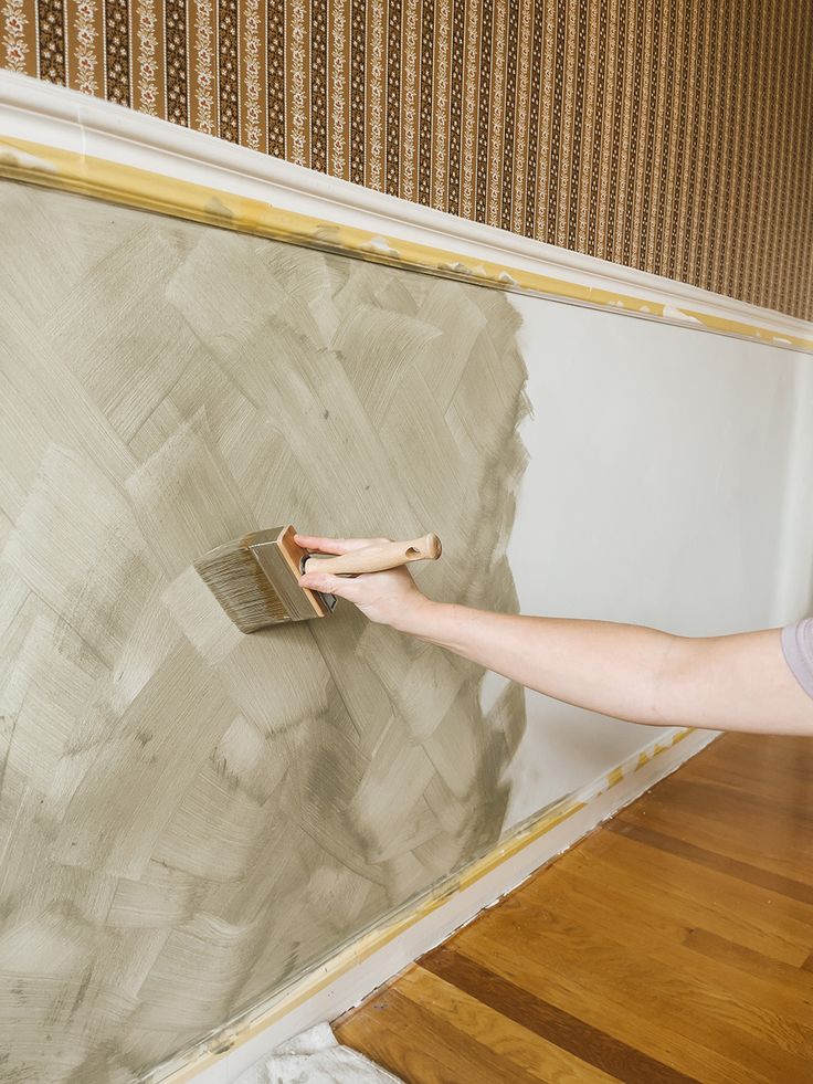 a woman using a brush to paint a wall