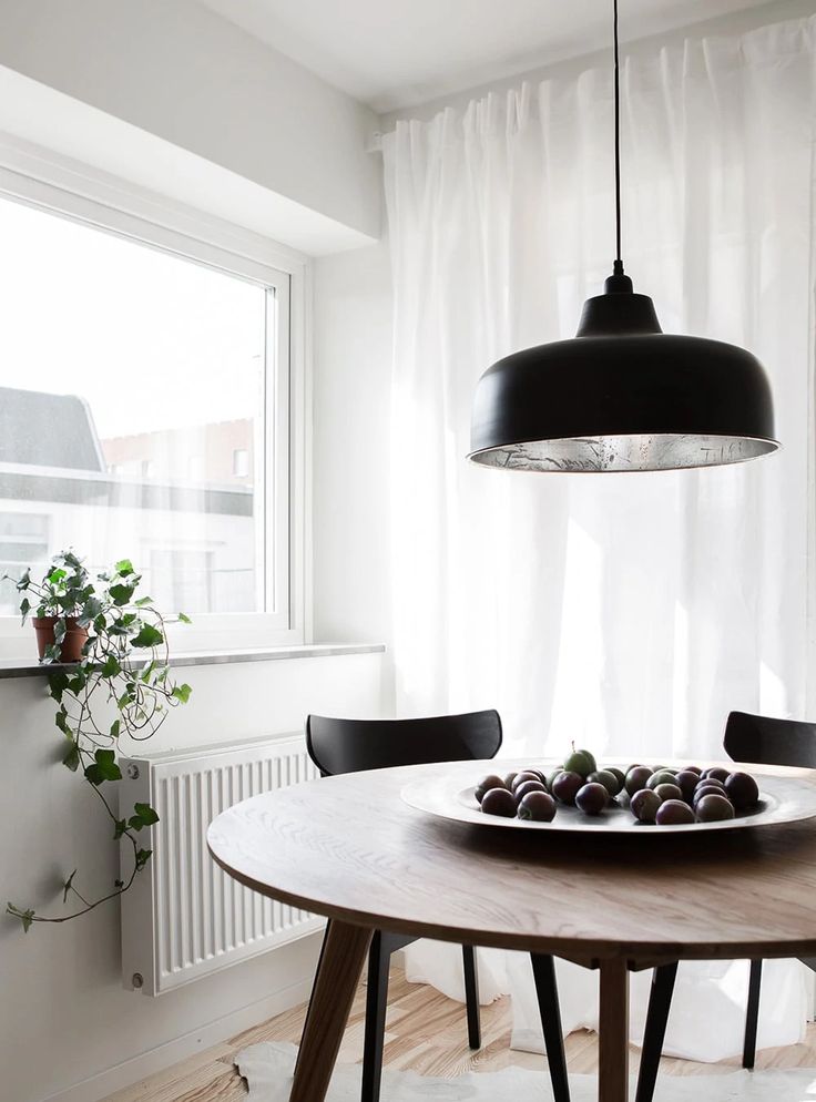 a wooden table topped with fruit under a black light hanging from a ceiling fixture over a window