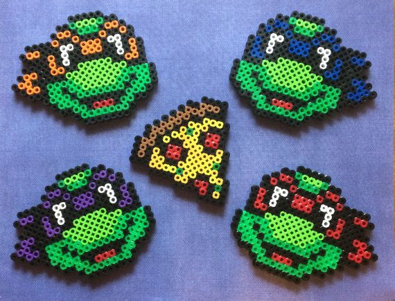 four perler bead teenage mutant turtles on a blue background, each with different colors and patterns