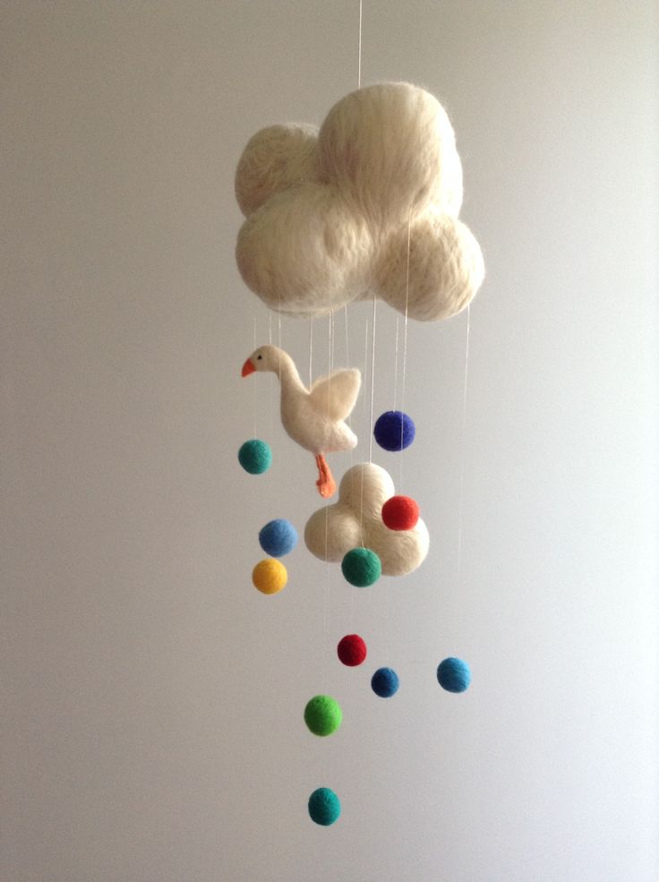 a white cloud mobile with colorful balls hanging from it's sides and a duck on the other side