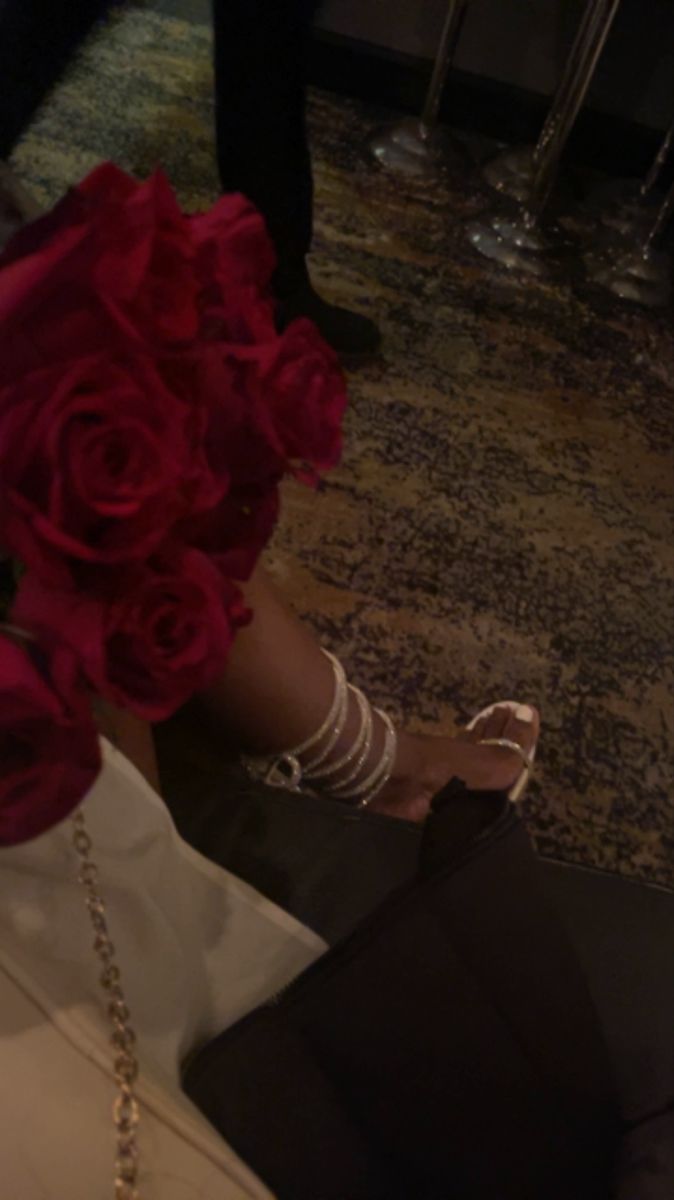 a woman sitting on the floor with red roses in her hair