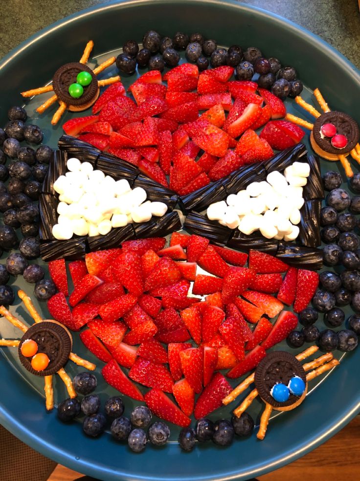 a platter filled with strawberries, blueberries and chocolate covered pretzels