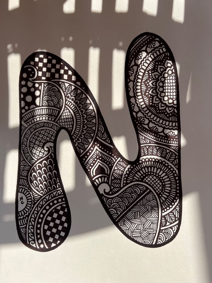 the letter n is made up of intricately designed paper and has a shadow cast on it