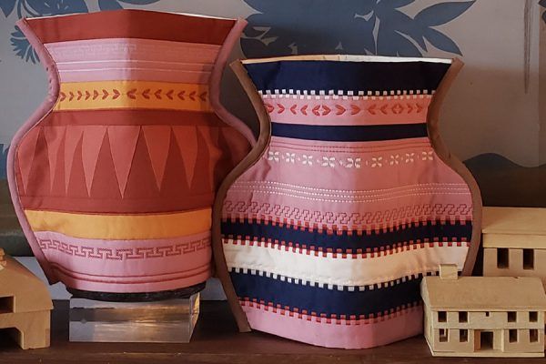 two vases sitting next to each other on top of a wooden table with toy houses