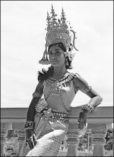 a woman dressed in an elaborate costume and headdress poses for the camera with her hands on her hips