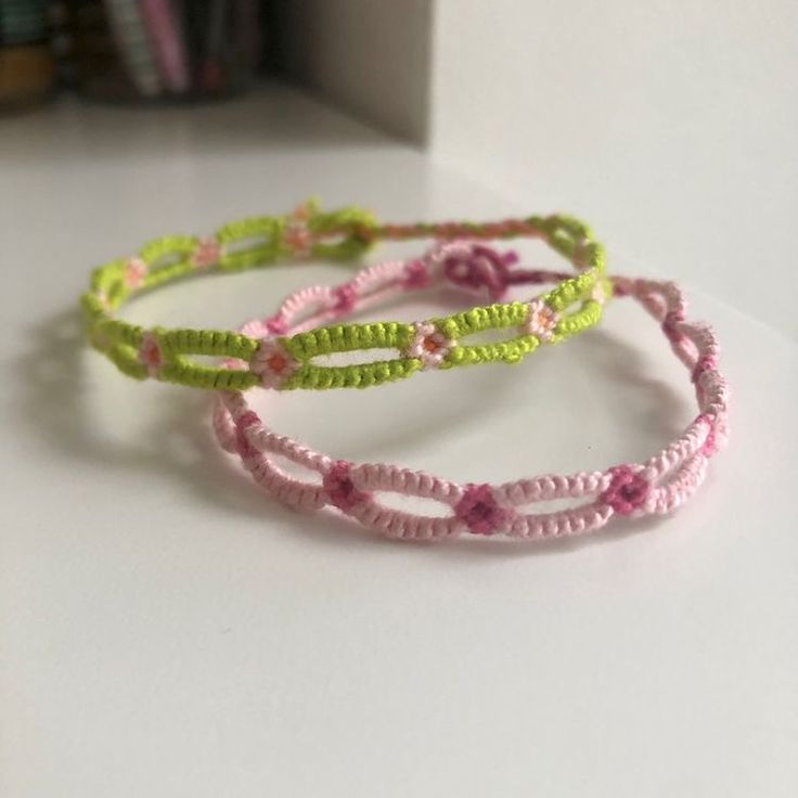 three bracelets with flowers on them sitting on top of a white table next to a bookshelf