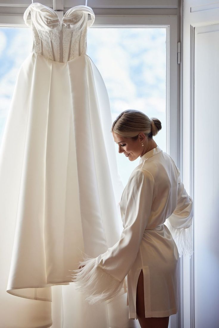 a woman standing in front of a dress hanging on a rack next to a window