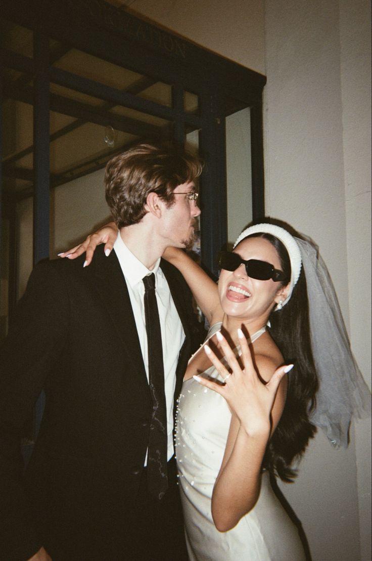 a man in a suit and tie standing next to a woman with her arm around him