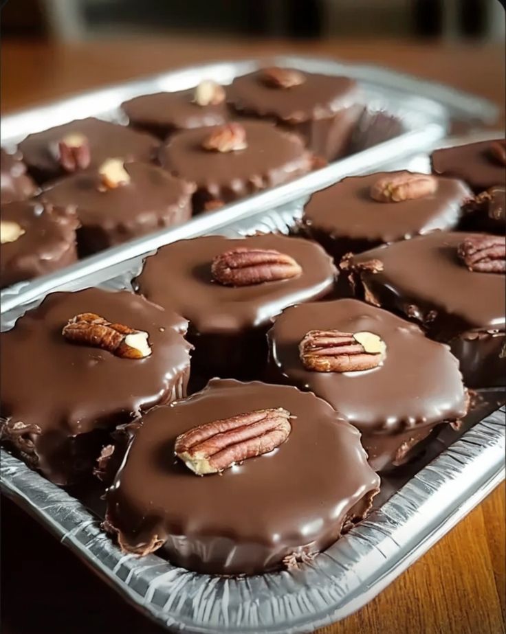 there are many pieces of chocolate with pecans on top in the tray and one is half eaten