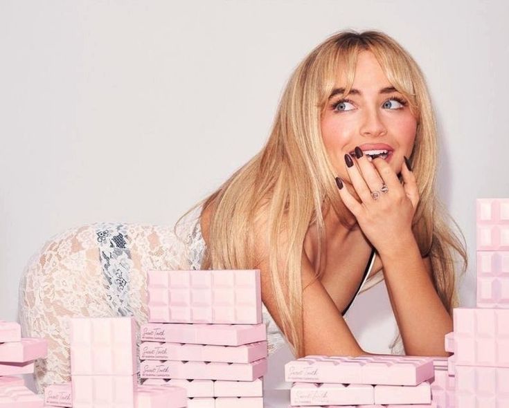 a woman laying on top of pink blocks with her hands in her mouth and looking up at the camera