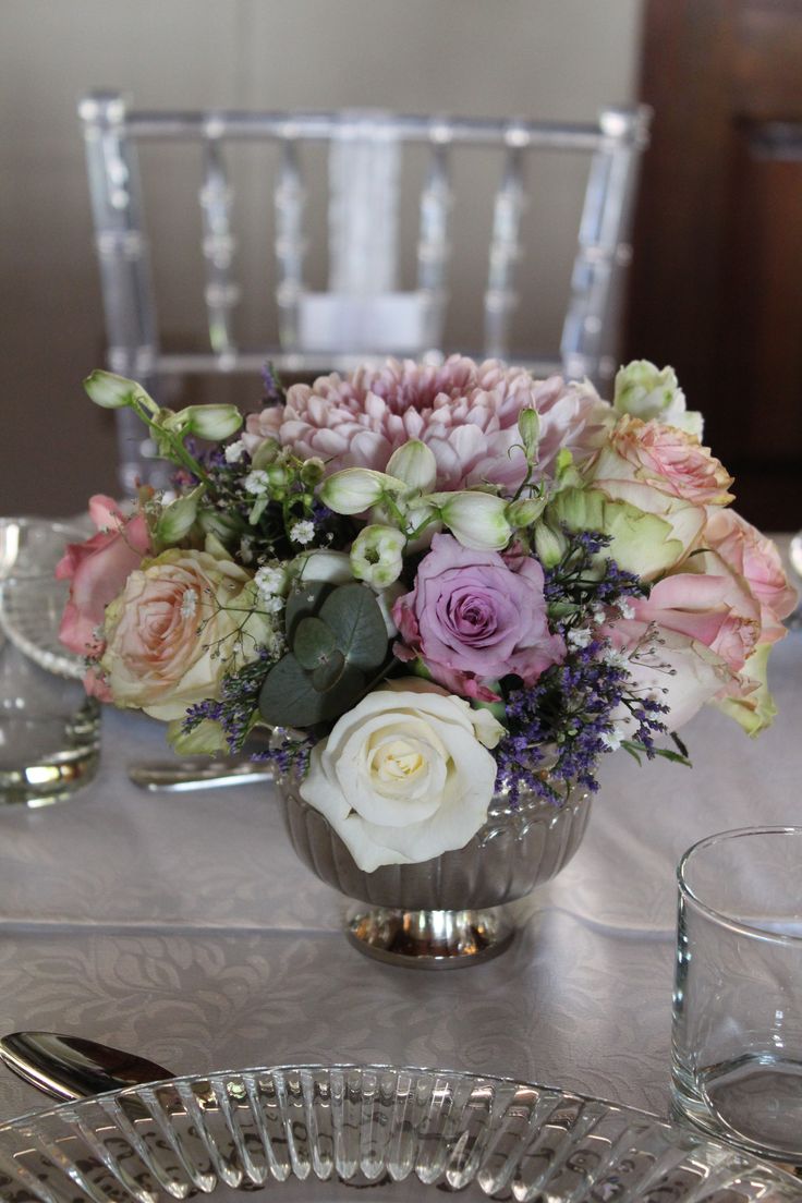 a vase filled with flowers sitting on top of a table next to two silver plates