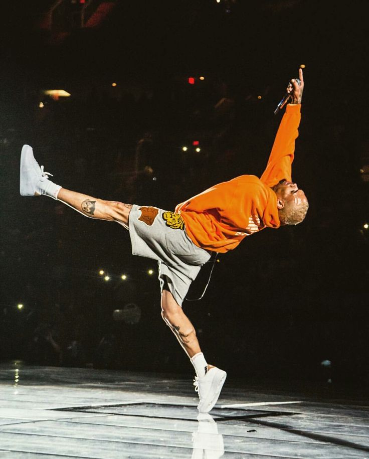 a man doing a handstand on top of a wooden floor in front of an audience