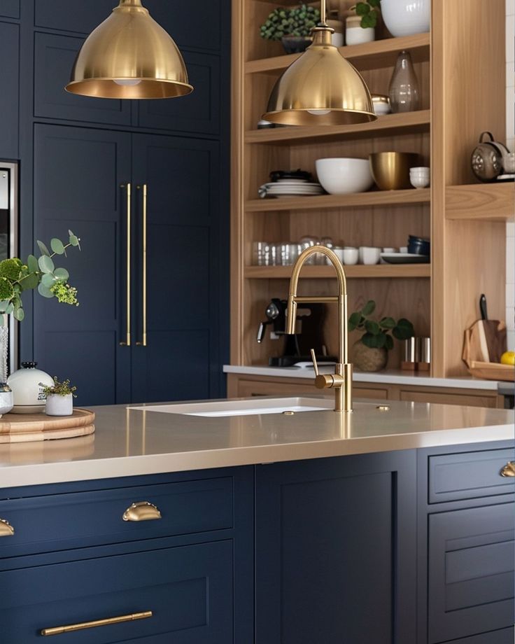 a kitchen with blue cabinets and gold accents, including brass pendant lights over the sink