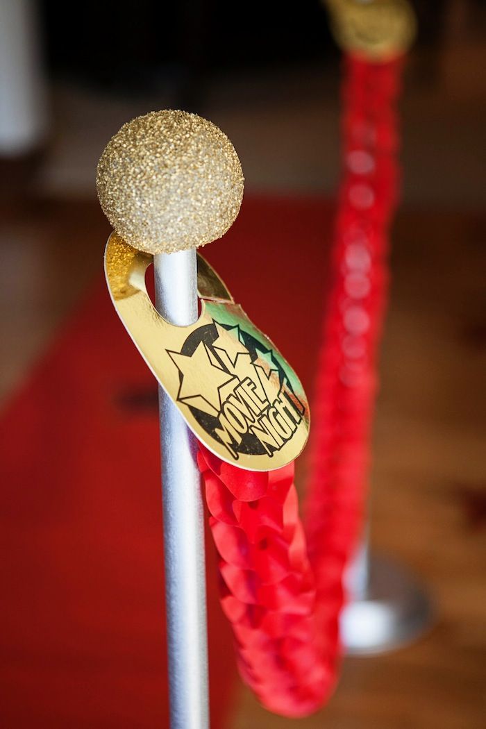 a red rope with a gold ring on it next to a metal pole that has two other ropes in front of it