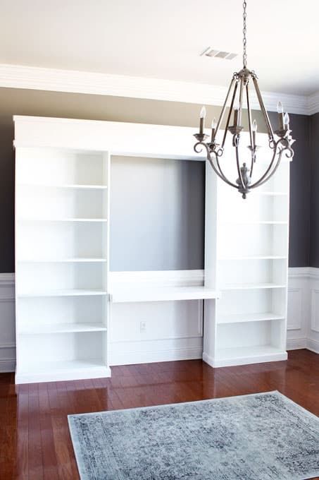 a chandelier hanging from the ceiling in a room with white bookshelves