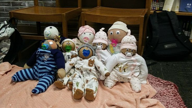 several stuffed animals are sitting on a blanket in front of some chairs and bookshelves