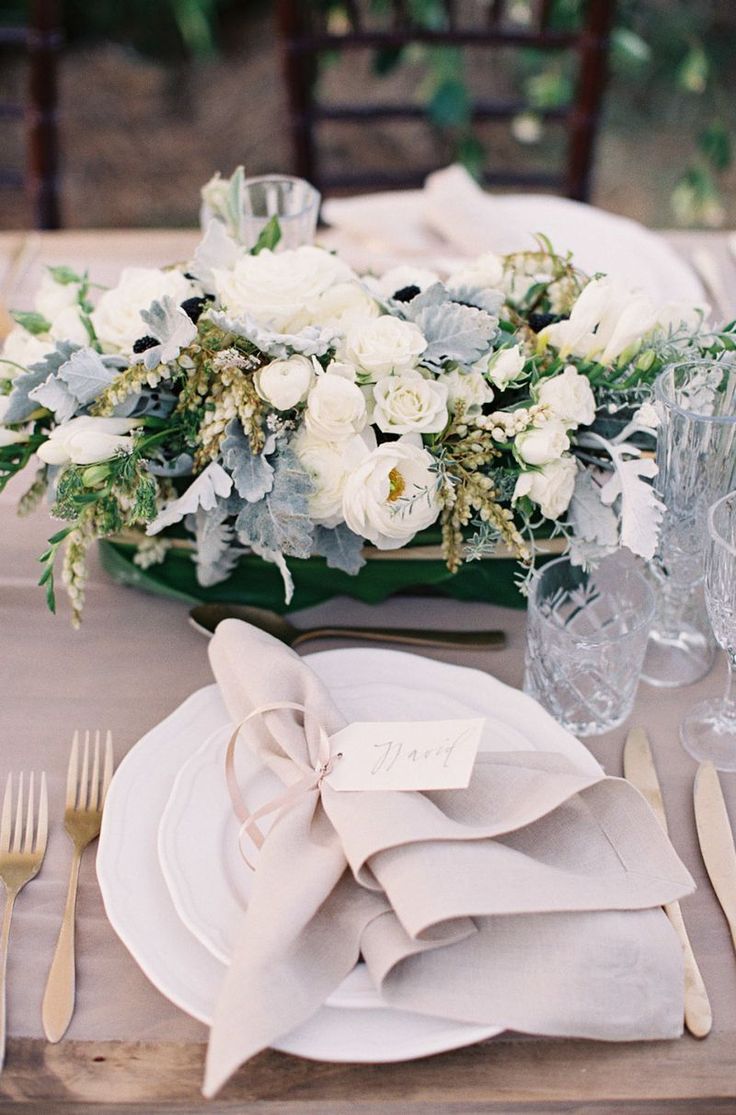 the table is set with white flowers and silverware