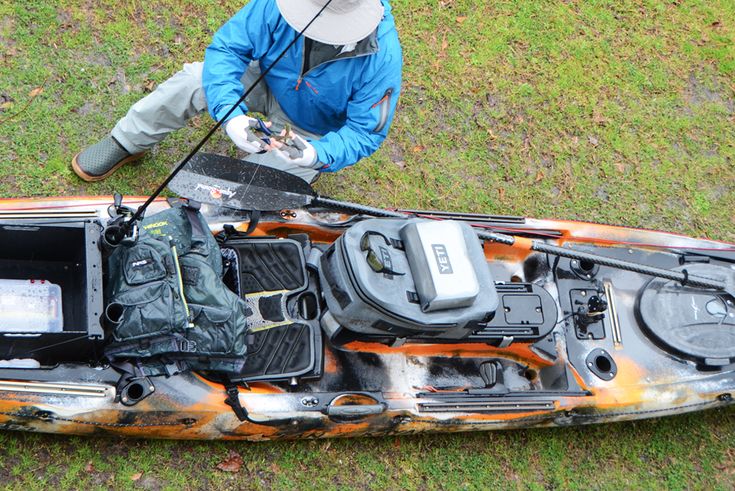 a man in blue jacket sitting on top of a kayak filled with gear and equipment