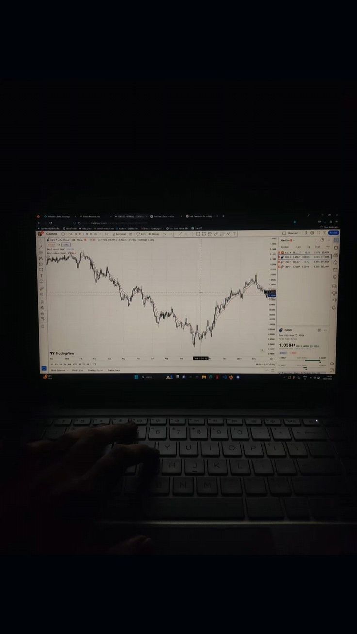 a laptop computer sitting on top of a desk with a screen showing an upward chart