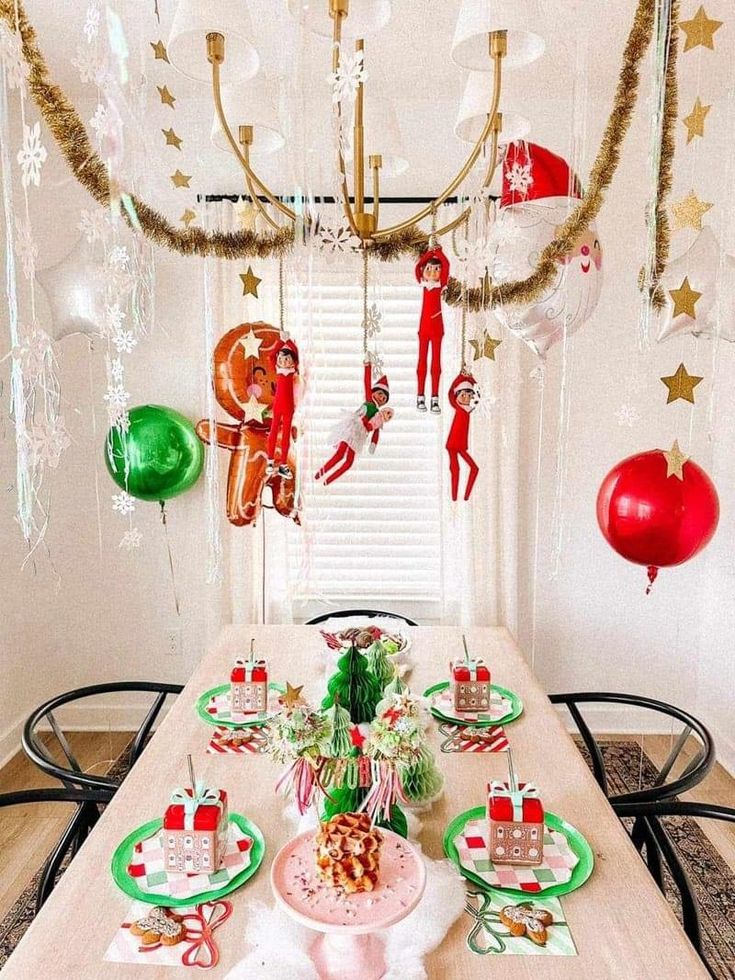 the table is set for christmas dinner with decorations hanging from the ceiling and elfs