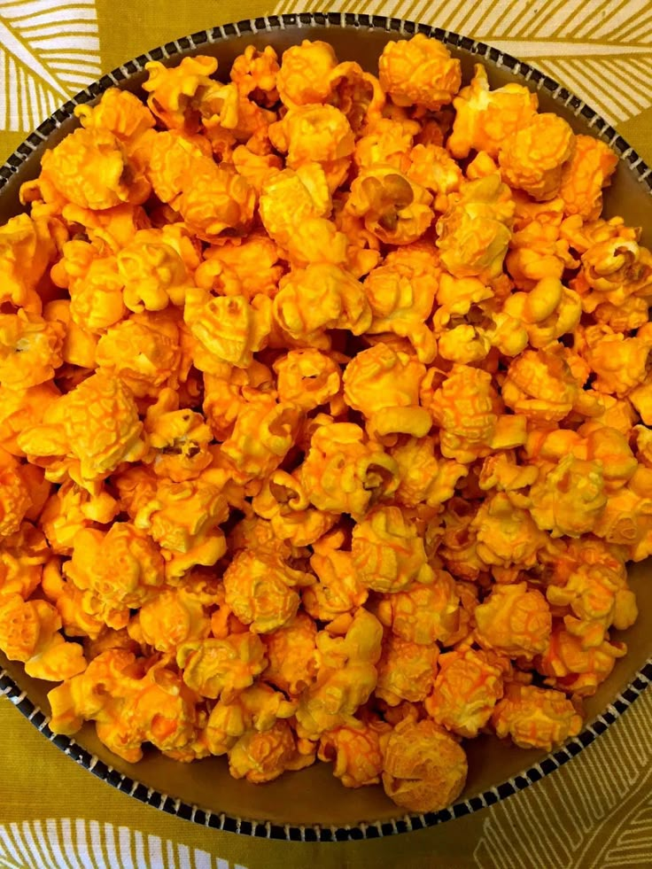 a bowl filled with yellow popcorn sitting on top of a tablecloth covered table cloth