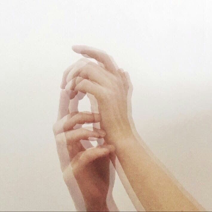 two hands reaching up into the air to grab something out of the foggy sky