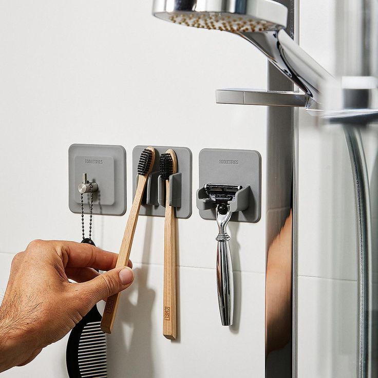 a person holding a toothbrush and comb in front of a wall mounted faucet