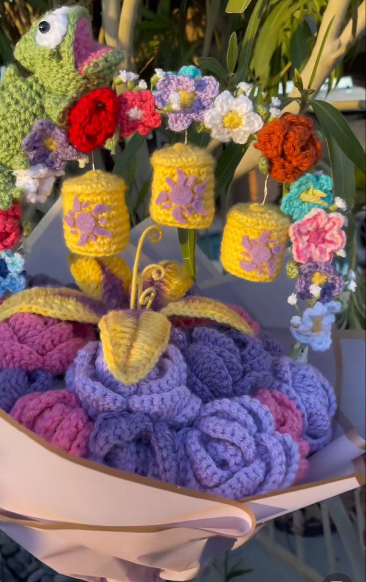 crocheted items are arranged on top of each other in a basket with flowers